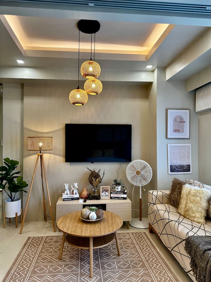Living area with sofa, wall-mounted TV and rattan pendant lights